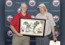 Two men holding a framed picture, smiling.