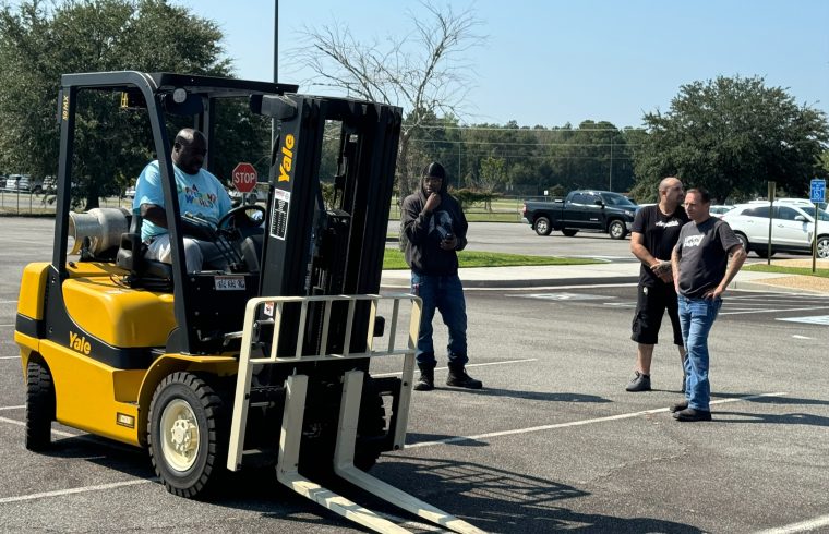 Yellow forklift with people observing in parking lot