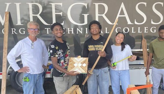 Students showcasing woodworking projects at college