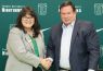 Two smiling people shaking hands at university backdrop