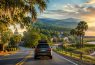 SUV driving along scenic coastal road at sunset