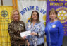 Three women holding a check at Rotary event.