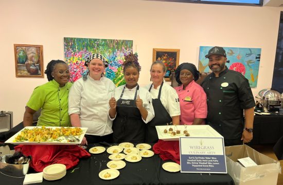 Catering team posing behind buffet of plated dishes