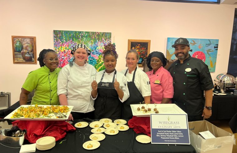 Catering team posing behind buffet of plated dishes